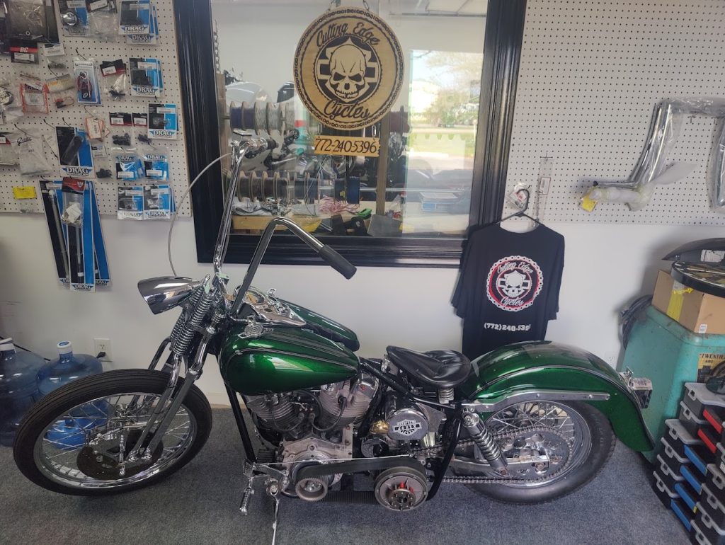 Custom motorcycle displayed in front of the Cutting Edge Cycles merchandise wall